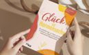 Zwei Hände halten das Buch "Glück ist Hormonsache" vor einem neutralen Hintergrund